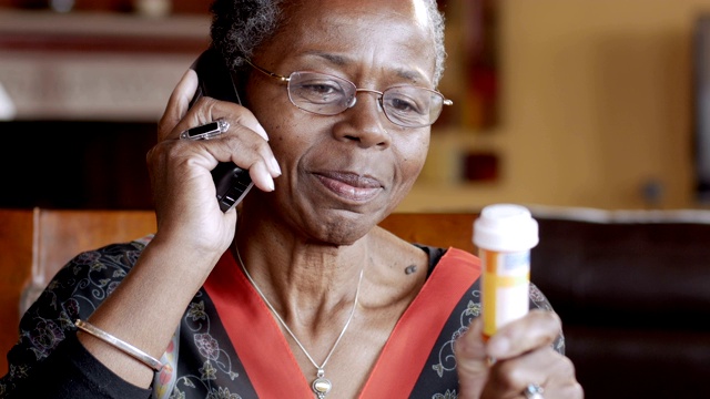 一位黑人老年妇女正在用无绳座机续药视频素材