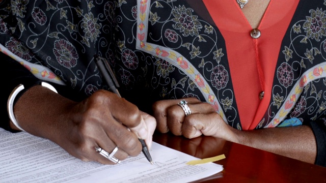 黑人老年妇女在法律文书上签名视频素材