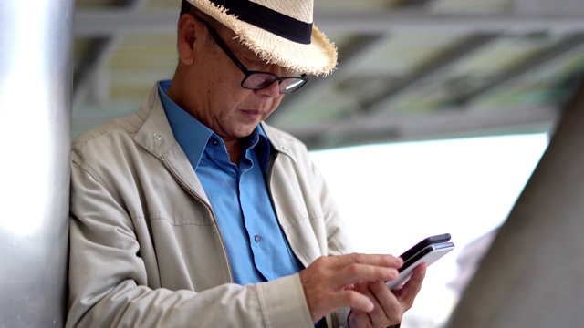 亚洲老人在旅行中使用手机视频素材