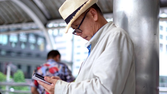 亚洲老人在旅行中使用手机视频素材