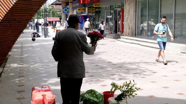穿着传统服装在街上卖花的男子/布加勒斯特视频下载