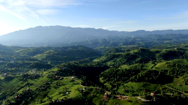 罗马尼亚喀尔巴阡(喀尔巴阡山脉/无人机拍摄)的乡村村庄，散落着房屋、山脉和天然林视频下载