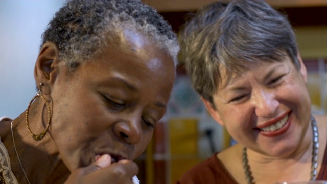 两个60岁以上的女性朋友在一个聚会上一起吃喝大笑视频素材