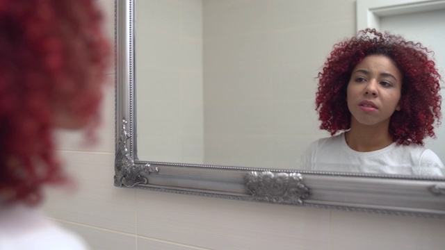 少女捏着青春痘，在镜子里看着自己的脸，缺乏安全感视频素材