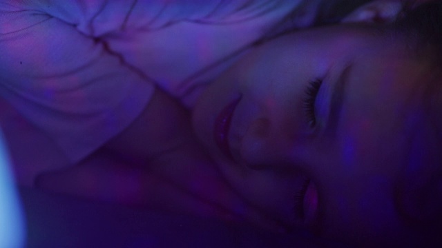 慢镜头里可爱的小女孩带着彩灯安静地睡在床上视频下载