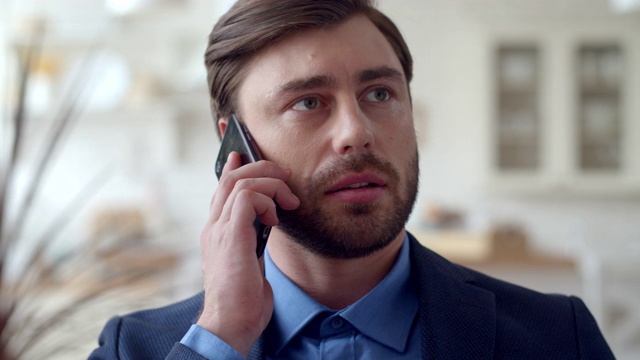 一个严肃的商人在家里的办公室里用手机说话。人说电话。视频素材