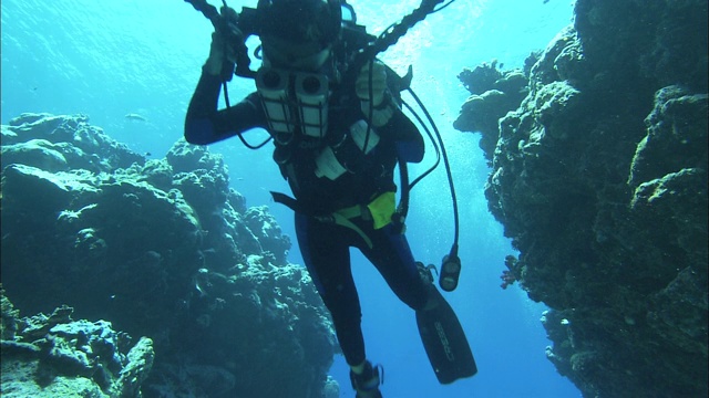一名潜水员带着水下摄像机游过裂缝。视频下载