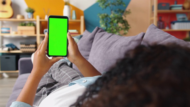 美国黑人妇女看绿色智能手机屏幕内容的后视图视频素材
