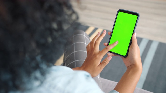 后视图的女人黑发使用绿色屏幕智能手机触摸屏视频素材
