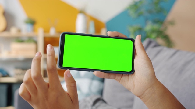女孩的手在室内触摸绿色垂直智能手机屏幕的慢动作视频素材
