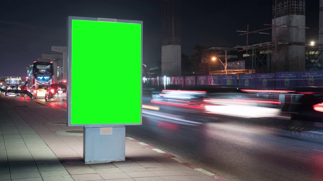 时间流逝。有绿色屏幕的广告牌，位于繁忙的街道上。汽车在晚上行驶。视频下载