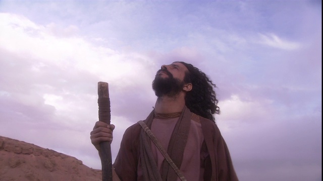 一名身着圣经服饰的男子手持一根棍子，望向天空。视频下载