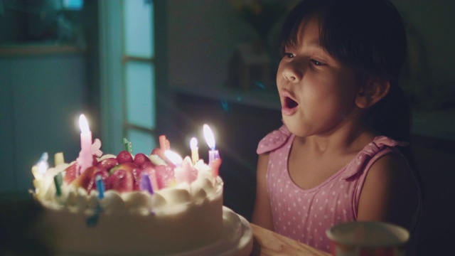 快乐的小女孩吹灭生日蛋糕上的蜡烛视频素材