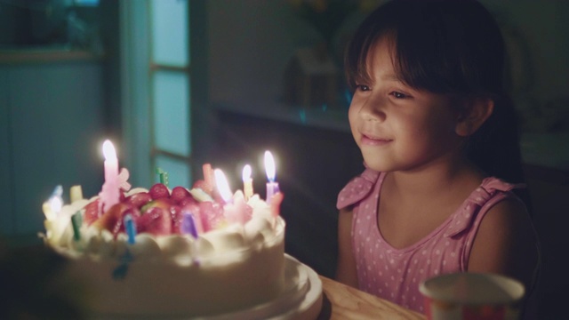 快乐女孩吹灭生日蛋糕上的蜡烛视频素材