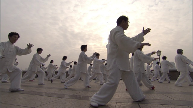 东方明珠塔隐约出现在背景中，太极练习者在上海的一个院子里练习。视频下载