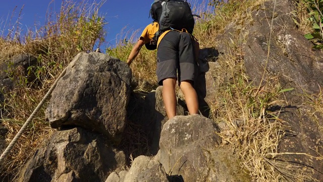 一个男人爬上岩石山的后视图视频下载