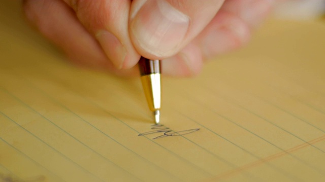特写人物用钢笔在黄色笔记本上签名视频下载