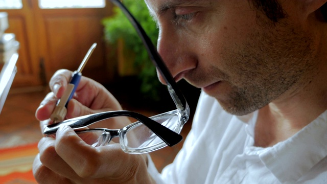 男人用手持的小螺丝刀修理眼镜视频下载