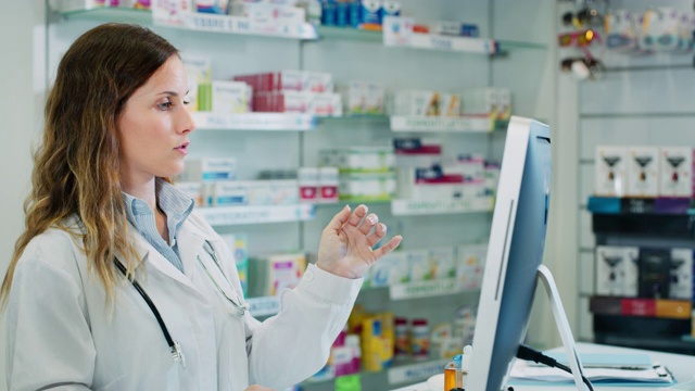 一个年轻的女药剂师在药店的电脑里为病人寻找药物的慢动作视频素材