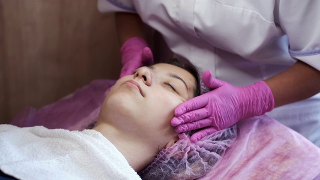 美容师在美容院给女士涂抹面霜和按摩视频下载