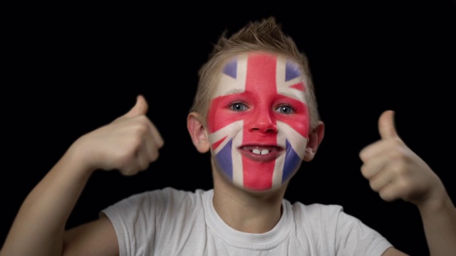 快乐的男孩为他最喜欢的英格兰队的胜利而高兴。脸上涂着民族色彩的孩子。视频下载