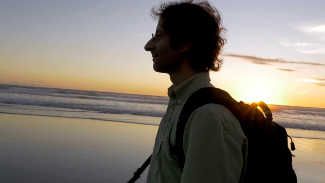 一个背着背包在海滩上漫步的旅行者的手视频素材