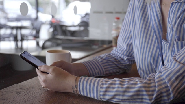 一名女性在咖啡店使用智能手机视频下载