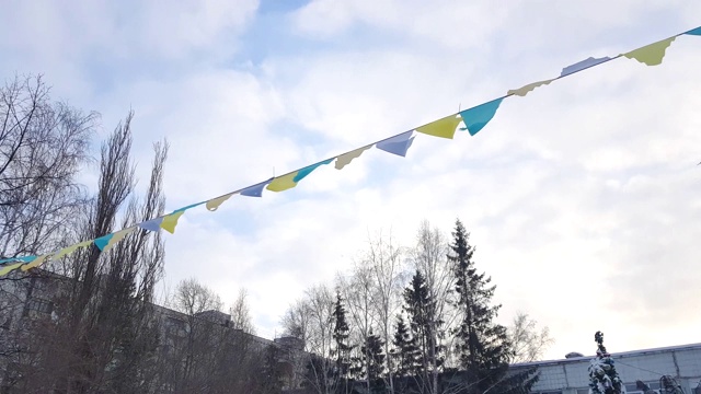 三角形的五彩旗子以花环的形式呈现，节日的嘉年华装饰，多云的蓝天上的旗帜在刮风的日子，4K视频。视频下载