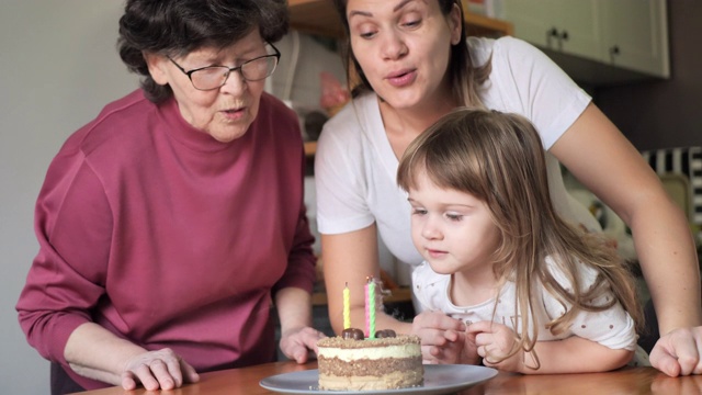 老奶奶和孙女在生日蛋糕上吹蜡烛视频下载