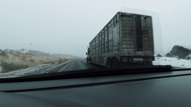 车辆视角拍摄在超车车道上超过一辆半卡车，并合并到右车道70号州际公路在一个下雪的日子在冬天视频素材