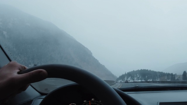 冬日里，一个人在科罗拉多落基山脉70号州际公路上驾驶，驾驶着汽车的方向盘视频素材