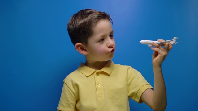 快乐的孩子在蓝色的背景上玩着玩具飞机视频素材