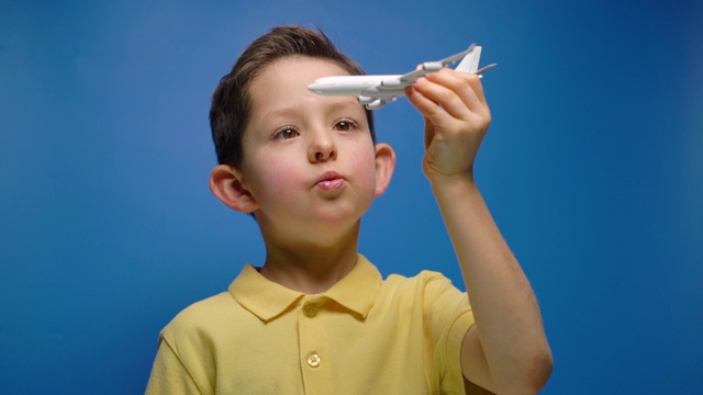 快乐的孩子在蓝色的背景上玩着玩具飞机视频素材