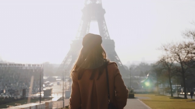 镜头跟随快乐优雅美丽的女人走在史诗般的阳光下的巴黎艾菲尔铁塔附近特罗卡德罗慢镜头视频素材
