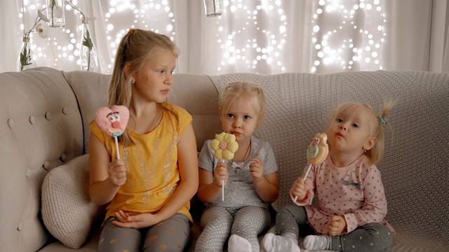 三个可爱的女孩正兴致勃勃地吃着棒棒糖和糖果视频下载