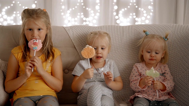 三个女孩坐在舒适的公寓的沙发上吃着棒棒糖视频下载