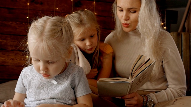 一个女人给她两个孩子的女儿读书视频素材