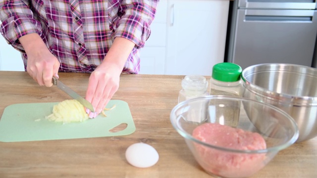 家庭主妇把洋葱切成小块，妇女往菜里放洋葱视频素材