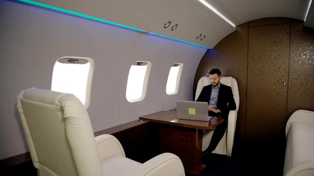 年轻时尚的律师、企业家、商人正坐在飞机内部使用笔记本电脑视频素材
