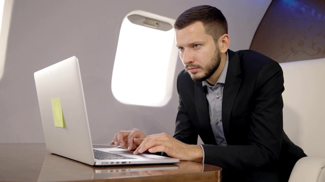 成功的年轻律师商人在飞行中用笔记本电脑工作，坐在企业家飞机上视频下载