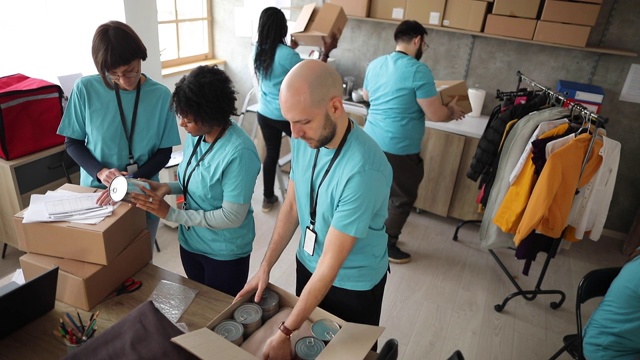 不同的志愿者在慈善食品银行包装捐赠箱视频素材