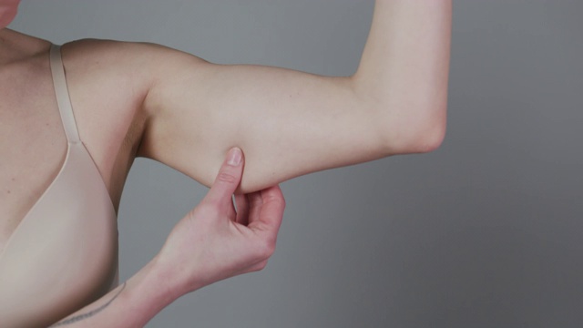 胖女人捏上臂脂肪孤立在灰色背景。特写白种人女性的手检查松弛的皮肤。身体控制，是时候开始节食减肥了视频下载