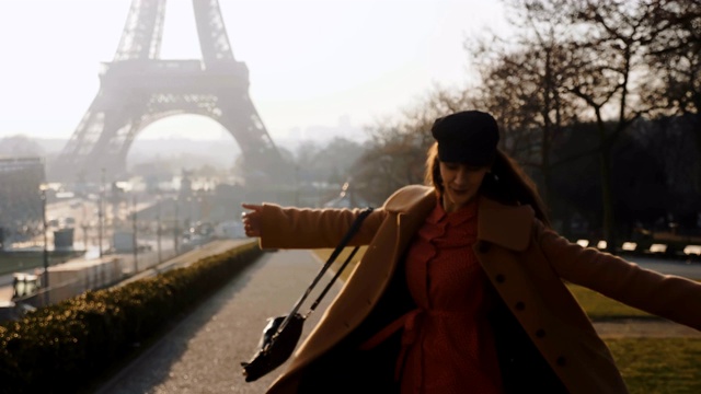 镜头跟随快乐快乐的美丽女子在史诗般的阳光明媚的巴黎埃菲尔铁塔中漫步、旋转的度假慢镜头视频素材