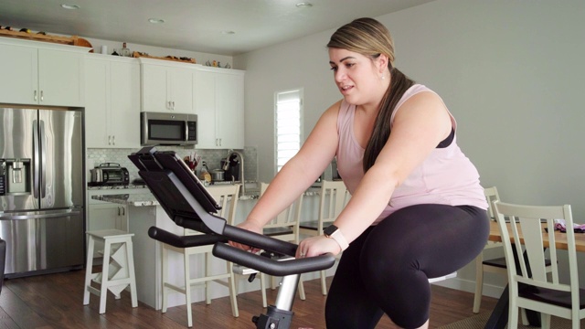 在家里使用健身自行车的妇女视频素材