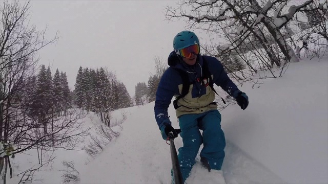 一名男子用自拍杆在山上滑雪并撞车的视频。视频下载