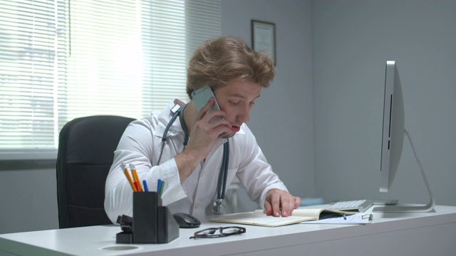 医生坐在医院的桌子旁打电话视频素材