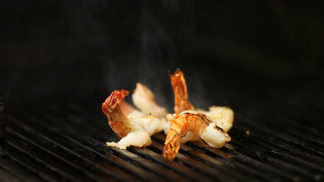 近距离的库克翻转烟熏虾烧烤。视频素材