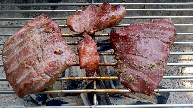 多汁的牛肋眼牛排在热烤架上与木炭和火焰视频下载