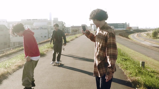滑板爱好者拍摄朋友表演滑板技巧(慢镜头)视频素材