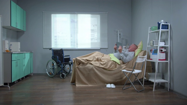 一名男子躺在医院的病床上，用平板电脑观看，情绪激动视频素材